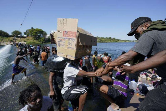 Haitian migrants use a dam to cross to and from the United States from Mexico, Friday, September 17, 2021, in Del Rio, Texas.