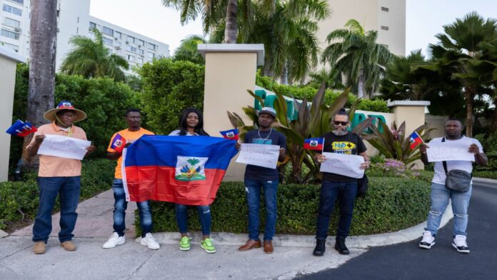 Protesters holding Haitian national flags and handmade signs with messages demanding Haiti's Prime Minister Ariel Henry resign, gather outside of the Marriott Hotel where they believe Henry is staying, in San Juan, Puerto Rico, Wednesday, March 6, 2024.